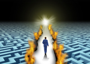 Innovative leadership and trail blazing or trailblazing business concept with a businessman walking through a maze or labyrinth that is open due to a burning path as a symbol of creative solutions.